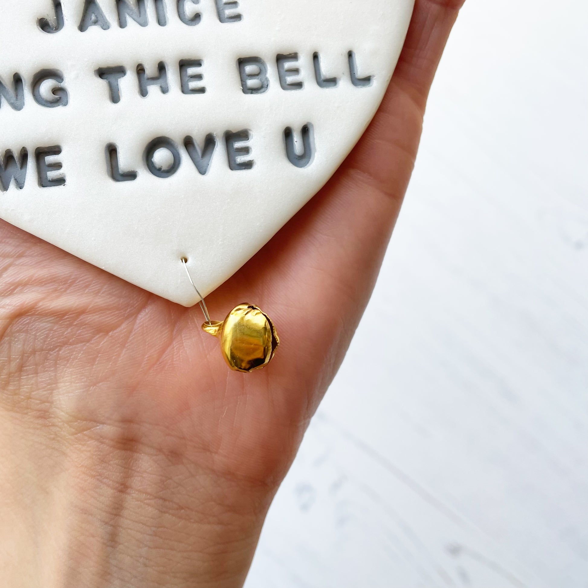 Personalised cancer survivor gift, pearlised white clay hanging heart with a grey lace edge at the top of the heart and a gold bell hanging below