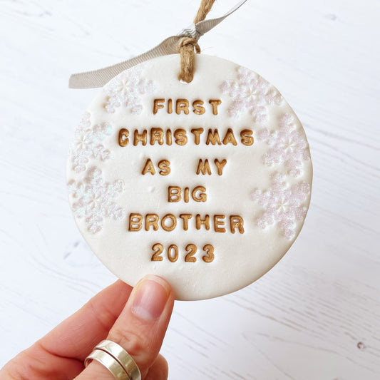 Personalised first Christmas as big brother bauble ornament, pearlised white clay round personalised with first Christmas as my big brother 2023 in gold paint, decorated with 3 iridescent glitter snowflakes on either side of the bauble