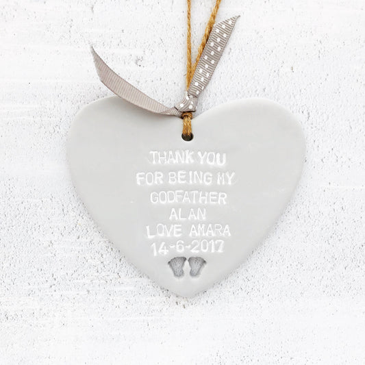 Personalised Godfather gift, grey clay hanging heart with baby feet cut out of the bottom, the heart is personalised with THANK YOU FOR BEING MY GODFATHER ALAN LOVE AMARA 14-6-2017