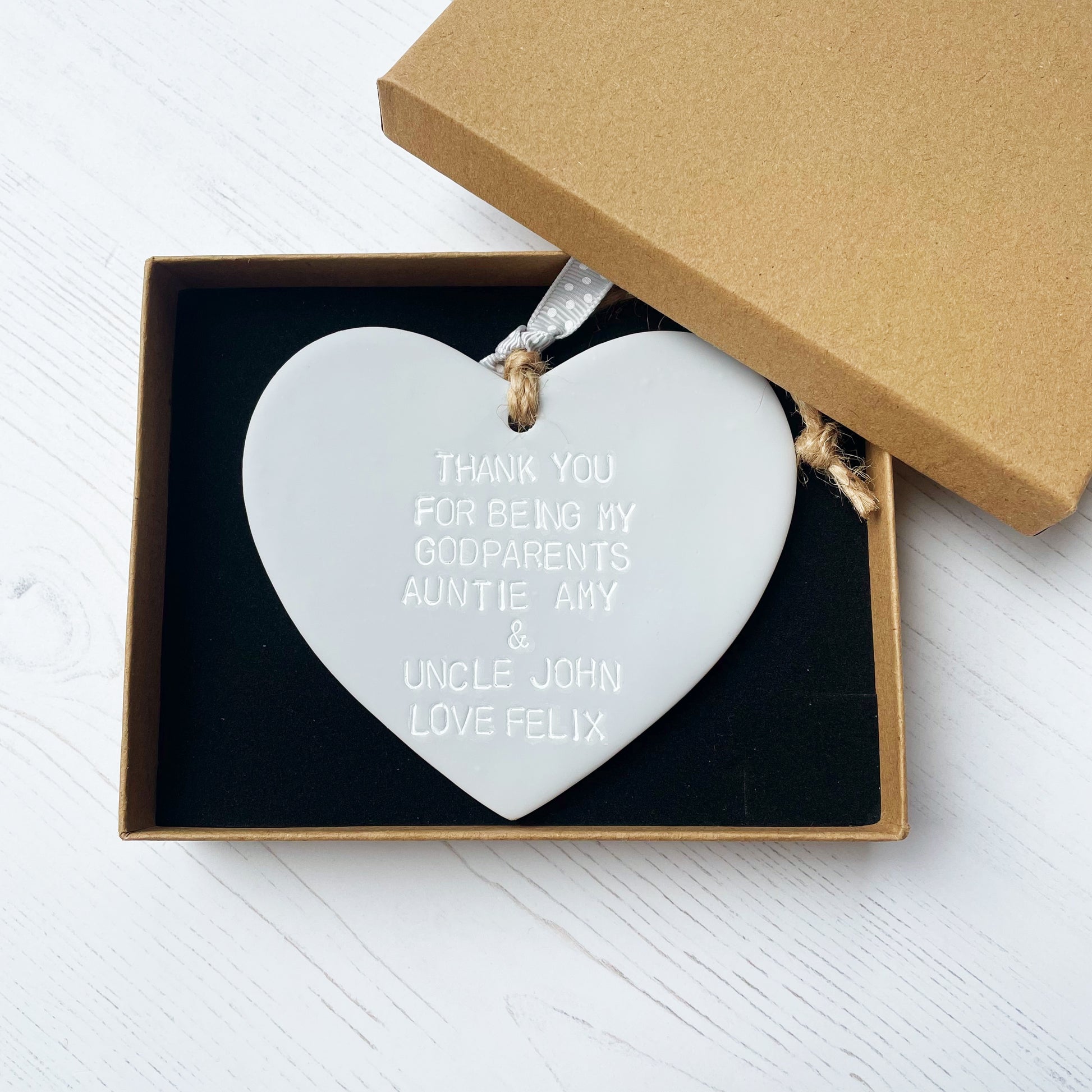 Personalised Godparents gift, grey clay hanging heart personalised in white with THANK YOU FOR BEING MY GODPARENTS AUNTIE AMY & UNCLE JOHN LOVE FELIX In a luxury brown Kraft gift box