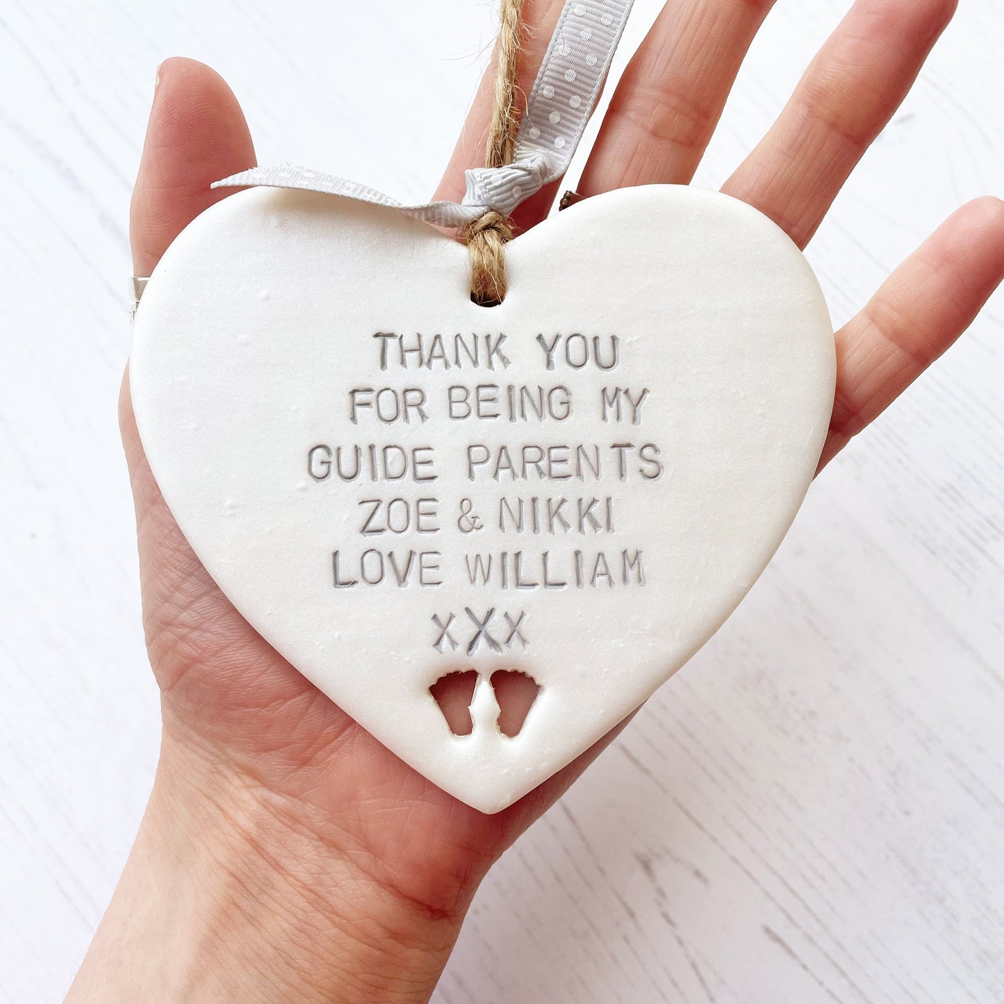Personalised guide parents gift, pearlised white clay hanging heart with baby feet cut out of the bottom, the heart is personalised with THANK YOU FOR BEING MY GUIDE PARENTS ZOE & NIKKI LOVE WILLIAM xXx