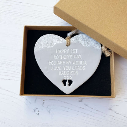Personalised first Mother’s Day gift, grey clay hanging heart with baby feet cut out at the bottom of the heart and a white lace edge at the top of the heart, the heart is personalised with HAPPY 1ST MOTHER’S DAY, YOU ARE MY WORLD, LOVE YOU LOADS MADDISON XXX