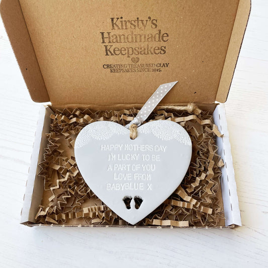 Personalised first Mother’s Day gift, grey clay hanging heart with baby feet cut out at the bottom of the heart and a white lace edge at the top of the heart, the heart is personalised with HAPPY MOTHER’S DAY I’M LUCKY TO BE A PART OF YOU LOVE FROM BABYBLUE X