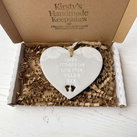 Personalised first Mother’s Day gift, grey clay hanging heart with baby feet cut out at the bottom of the heart and a white lace edge at the top of the heart, the heart is personalised with HAPPY MOTHER’S DAY LOVE FROM WILLIAM XXX