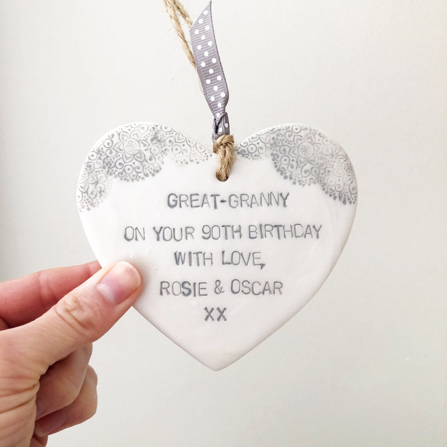 personalised pearlised white clay hanging hearts with a grey lace edge at the top of the heart, the heart is personalised with GREAT-GRANNY ON YOUR 90TH BIRTHDAY WITH LOVE, ROSIE & OSCAR XX