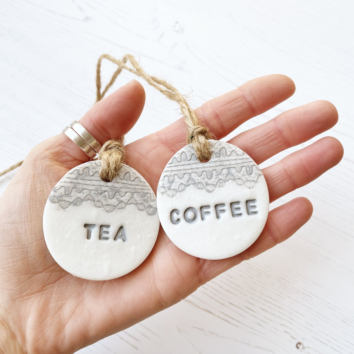 2 round pearlised white clay kitchen canister labels with coffee and tea stamped on each label in grey with a lace edge top