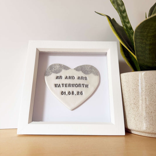 Personalised framed wedding gift, pearlised white clay heart with a grey lace edge at the top of the heart in a white box frame, the heart is personalised with MR AND MRS WATERWORTH 01.08.26