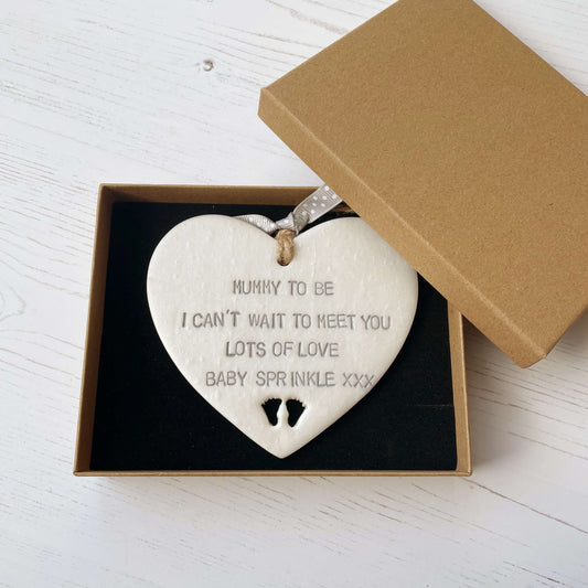 Personalised Mother’s Day gift, pearlised white clay hanging heart with baby feet cut out at the bottom of the heart, the heart is personalised with MUMMY TO BE I CAN’T WAIT TO MEET YOU LOTS OF LOVE BABY SPRINKLE XXX