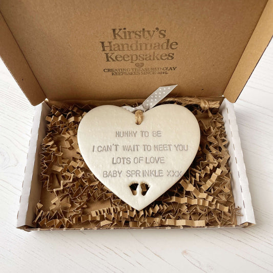Personalised Mother’s Day gift, pearlised white clay hanging heart with baby feet cut out at the bottom of the heart, the heart is personalised with MUMMY TO BE I CAN’T WAIT TO MEET YOU LOTS OF LOVE BABY SPRINKLE XXX