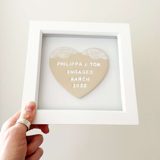 Personalised framed engagement gift, beige clay heart with a white lace edge at the top of the heart in a white box frame, the heart is personalised with PHILIPPA & TOM ENGAGED MARCH 2022
