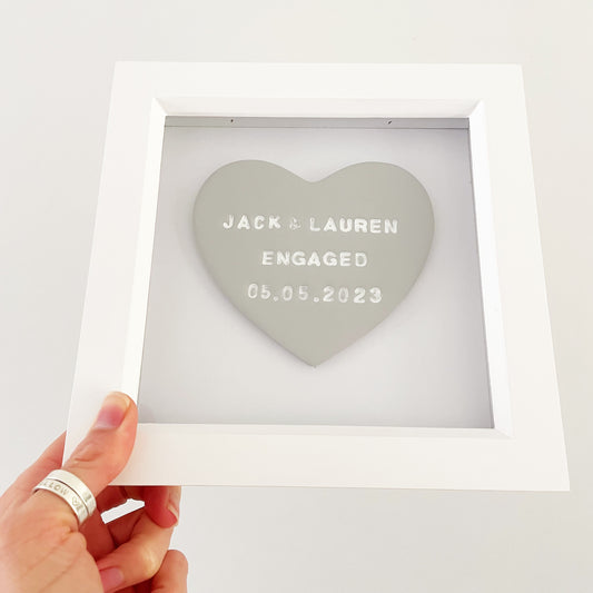 Personalised framed engagement gift, grey clay heart in a white box frame, the heart is personalised with JACK & LAUREN ENGAGED 05.05.2023