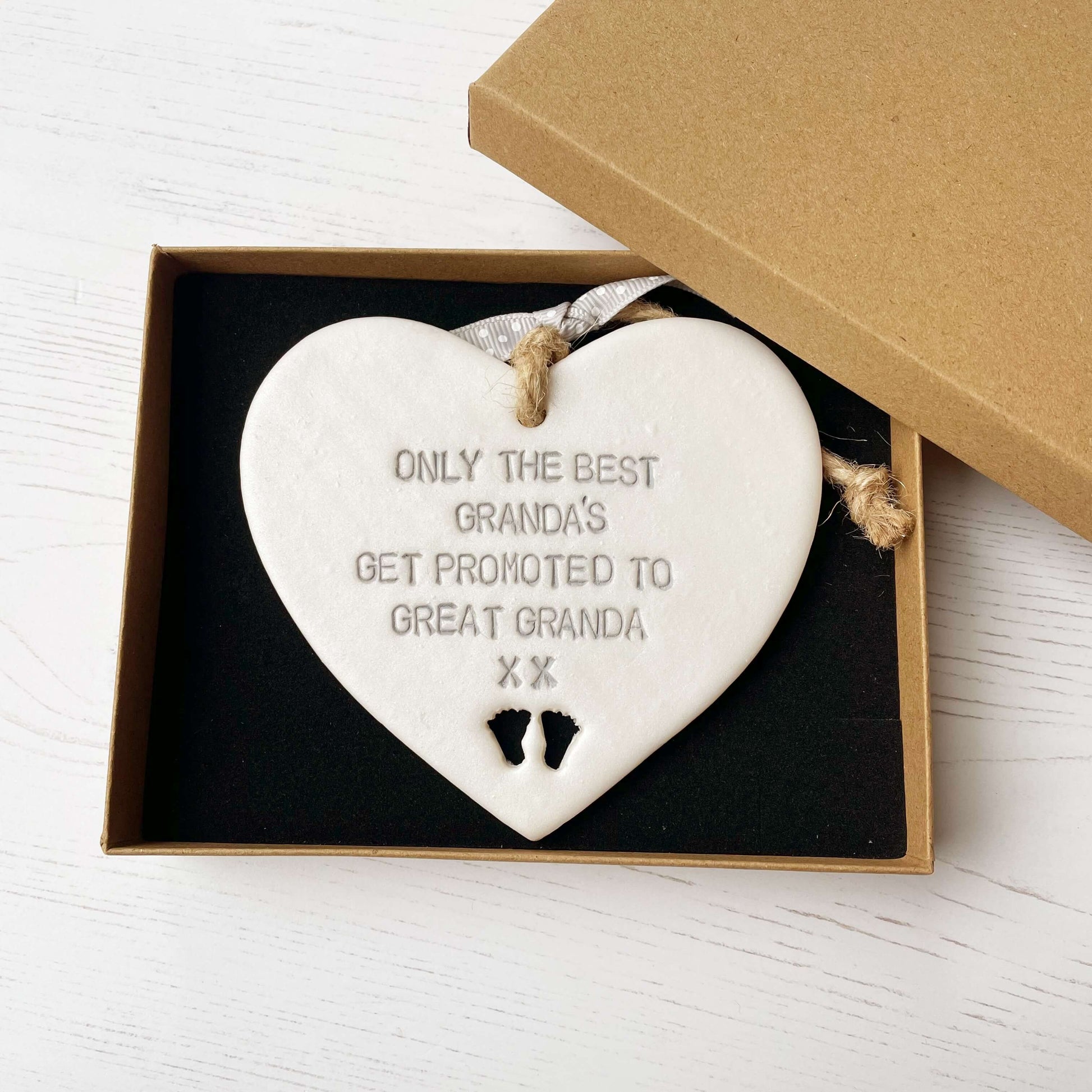 Pearlised white clay hanging heart pregnancy reveal with baby feet cut out of the bottom and grey personalisation, the heart is personalised with ONLY THE BEST GRANDA’S GET PROMOTED TO GREAT GRANDA XX