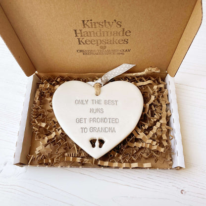 Pearlised white clay hanging heart with baby feet cut out of the bottom and grey personalisation, the heart is personalised with ONLY THE BEST MUMS GET PROMOTED TO GRANDMA