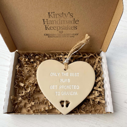 Beige clay hanging heart with baby feet cut out of the bottom and white personalisation, the heart is personalised with ONLY THE BEST MUMS GET PROMOTED TO GRANDMA