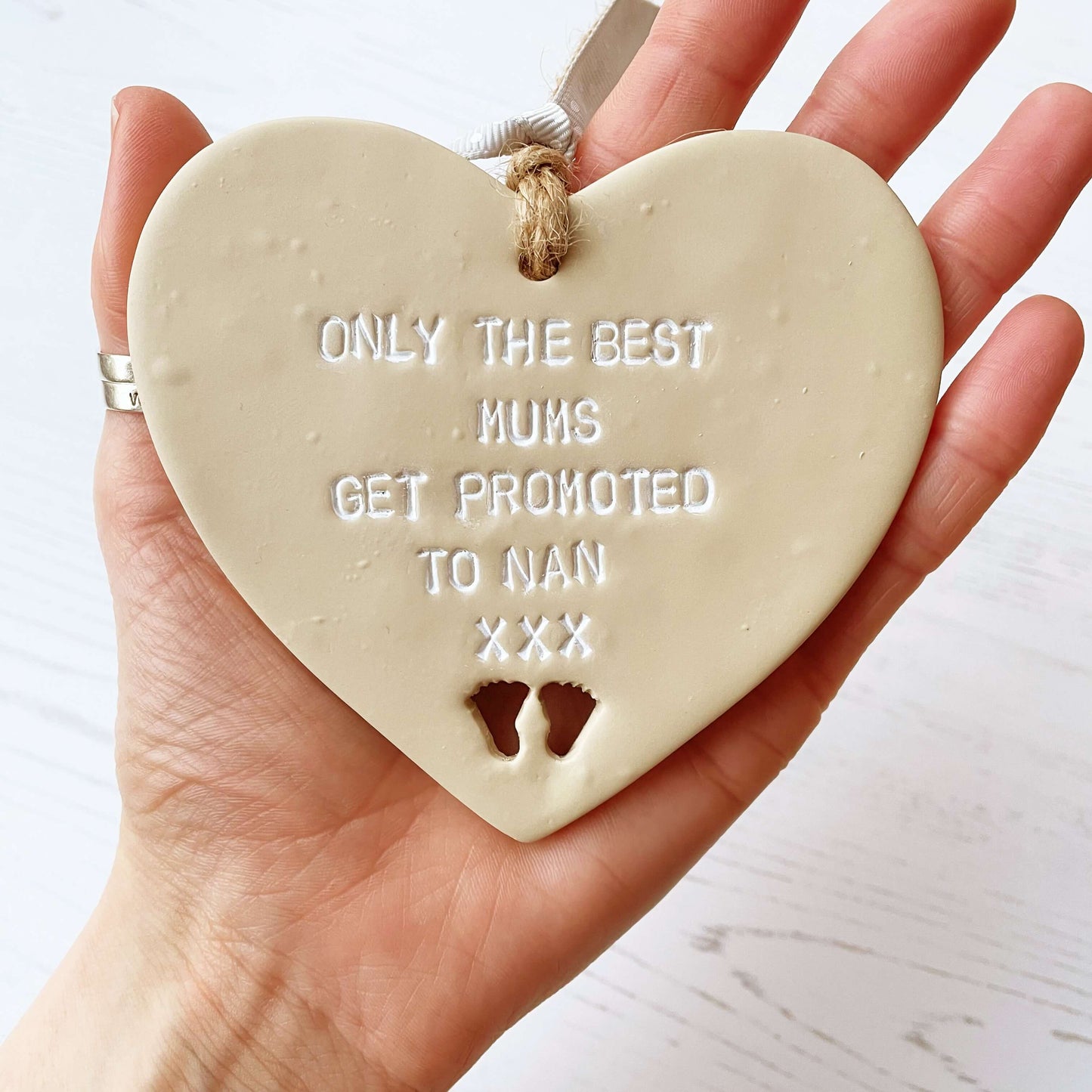 Beige clay hanging heart with baby feet cut out of the bottom and white personalisation, the heart is personalised with ONLY THE BEST MUMS GET PROMOTED TO NAN XXX