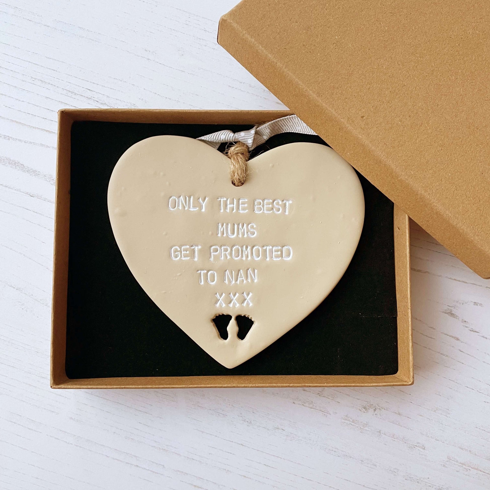 Beige clay hanging heart with baby feet cut out of the bottom and white personalisation, the heart is personalised with ONLY THE BEST MUMS GET PROMOTED TO NAN XXX