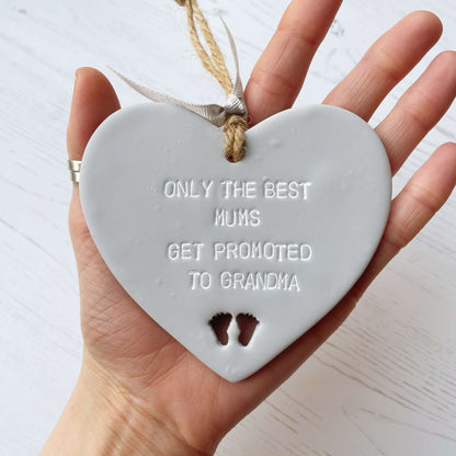 Grey clay hanging heart with baby feet cut out of the bottom and white personalisation, the heart is personalised with ONLY THE BEST MUMS GET PROMOTED TO GRANDMA