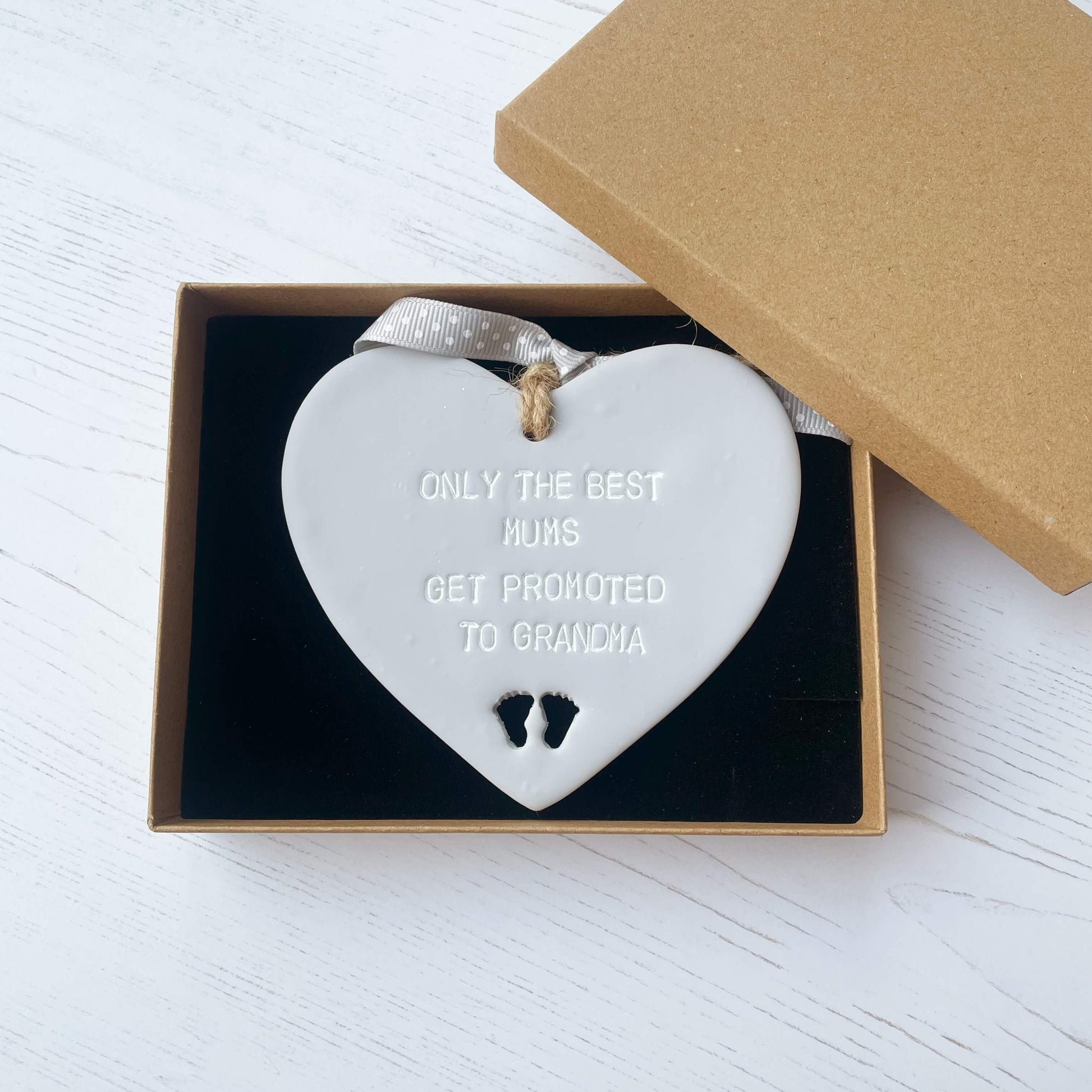 Grey clay hanging heart with baby feet cut out of the bottom and white personalisation, the heart is personalised with ONLY THE BEST MUMS GET PROMOTED TO GRANDMA