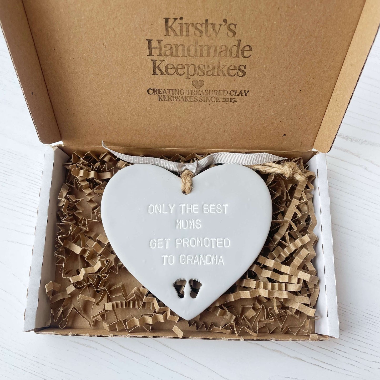 Grey clay hanging heart with baby feet cut out of the bottom and white personalisation, the heart is personalised with ONLY THE BEST MUMS GET PROMOTED TO GRANDMA