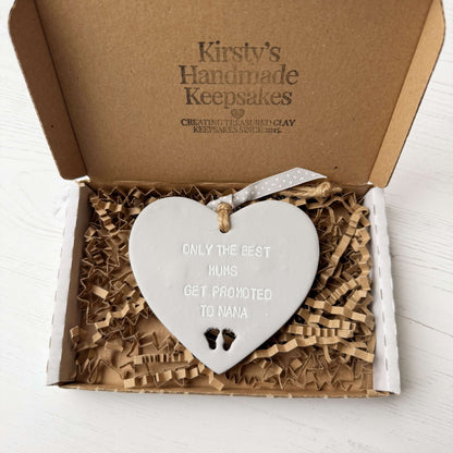 Grey clay hanging heart with baby feet cut out of the bottom and white personalisation, the heart is personalised with ONLY THE BEST MUMS GET PROMOTED TO NANA