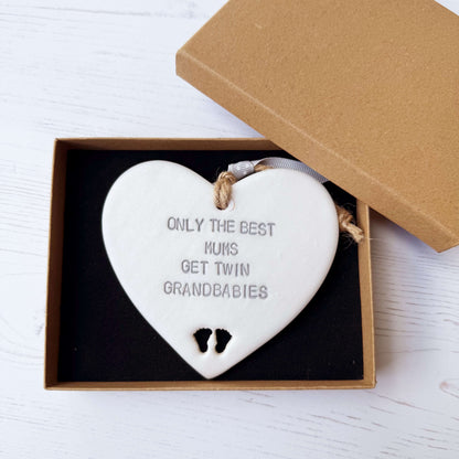 Pearlised white clay hanging heart with baby feet cut out of the bottom and grey personalisation, the heart is personalised with ONLY THE BEST MUMS GET TWIN GRANDBABIES