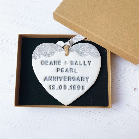 Personalised 30th Pearl anniversary gift, pearlised white clay hanging heart with a grey lace edge at the top of the heart, the heart is personalised with DEAN & SALLY PEARL ANNIVERSARY 12.08.1995