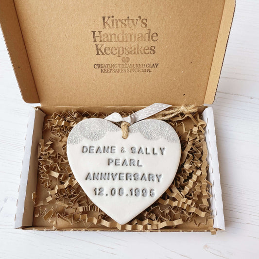 Personalised 30th Pearl anniversary gift, pearlised white clay hanging heart with a grey lace edge at the top of the heart, the heart is personalised with DEAN & SALLY PEARL ANNIVERSARY 12.08.1995