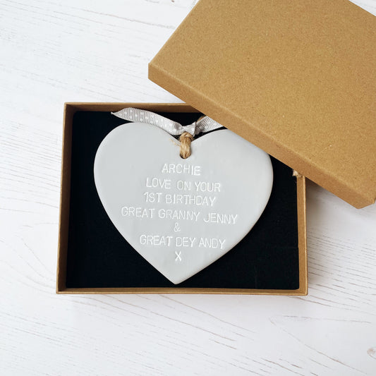 Personalised 1st birthday gift, grey clay hanging heart, the heart is personalised in white with ARCHIE LOVE ON YOUR 1ST BIRTHDAY GREAT GRANNY JENNY & GREAT DEY ANDY X