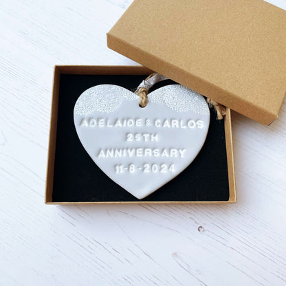 Personalised 25th anniversary gift, grey clay hanging heart with a white lace edge at the top of the heart, the heart is personalised with ADELAIDE & CARLOS 25TH ANNIVERSARY 11-8-2024