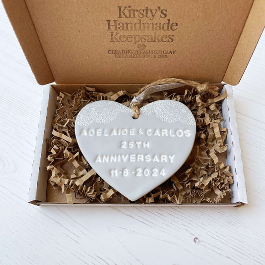 Personalised 25th anniversary gift, grey clay hanging heart with a white lace edge at the top of the heart, the heart is personalised with ADELAIDE & CARLOS 25TH ANNIVERSARY 11-8-2024