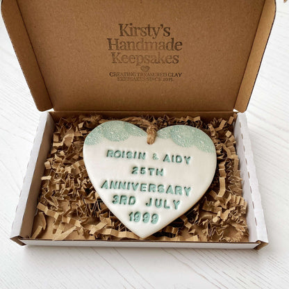 Personalised 25th anniversary gift, pearlised white clay hanging heart with a sage green lace edge at the top of the heart, the heart is personalised with ROISIN & AIDY 25TH ANNIVERSARY 3RD JULY 1999