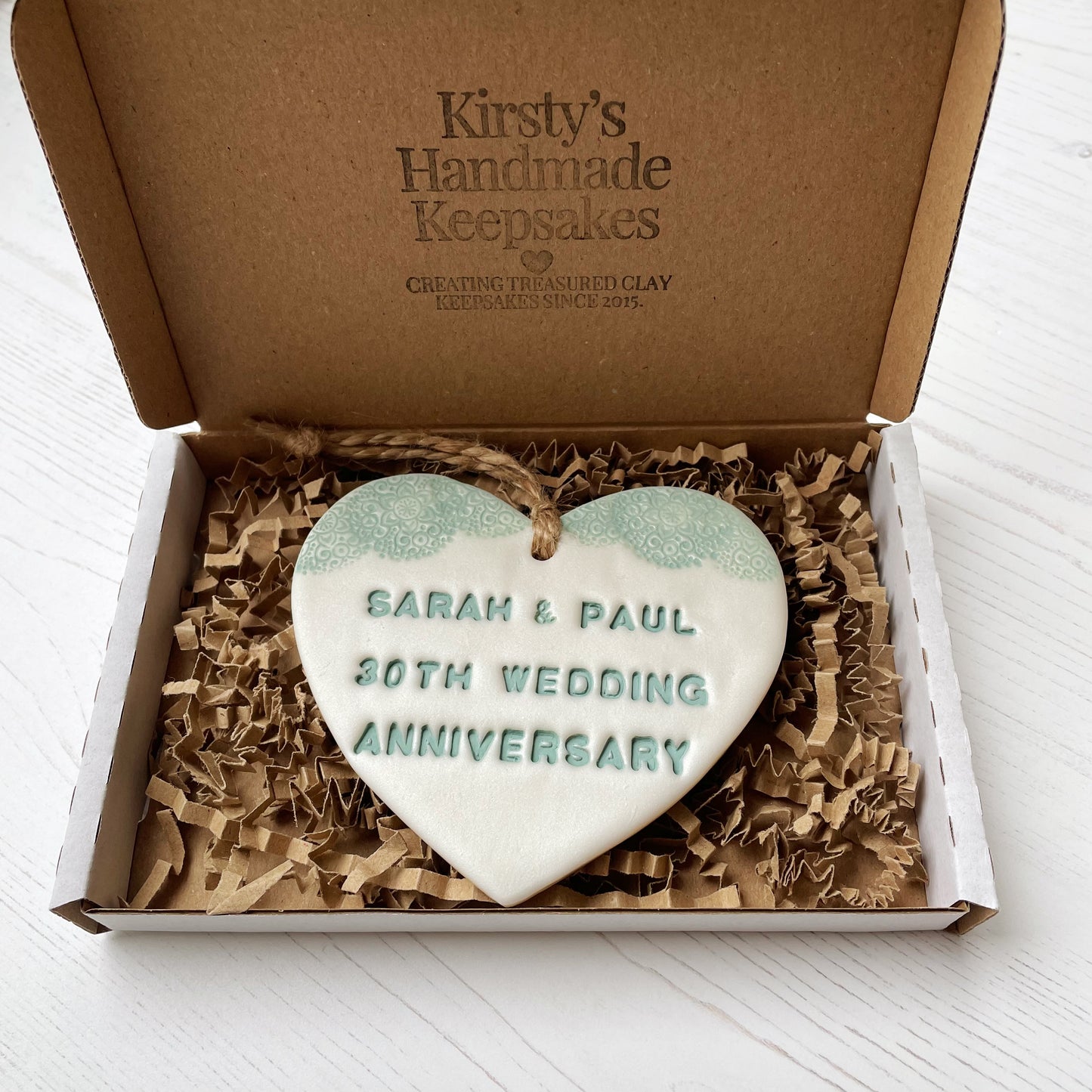 Personalised 30th anniversary gift, pearlised white clay hanging heart with a sage green lace edge at the top of the heart, the heart is personalised with SARAH & PAUL 30TH WEDDING ANNIVERSARY