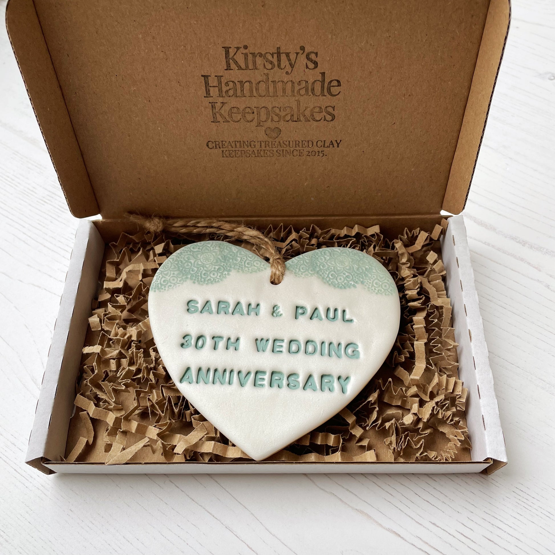 Personalised 30th anniversary gift, pearlised white clay hanging heart with a sage green lace edge at the top of the heart, the heart is personalised with SARAH & PAUL 30TH WEDDING ANNIVERSARY