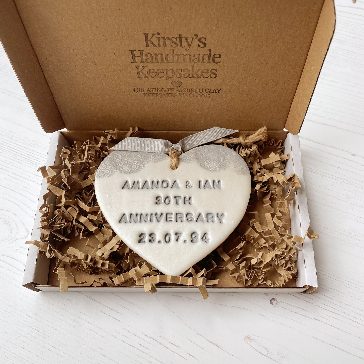 Personalised 30th Pearl anniversary gift, pearlised white clay hanging heart with a grey lace edge at the top of the heart, the heart is personalised with AMANDA & IAN 30TH ANNIVERSARY 23.07.94