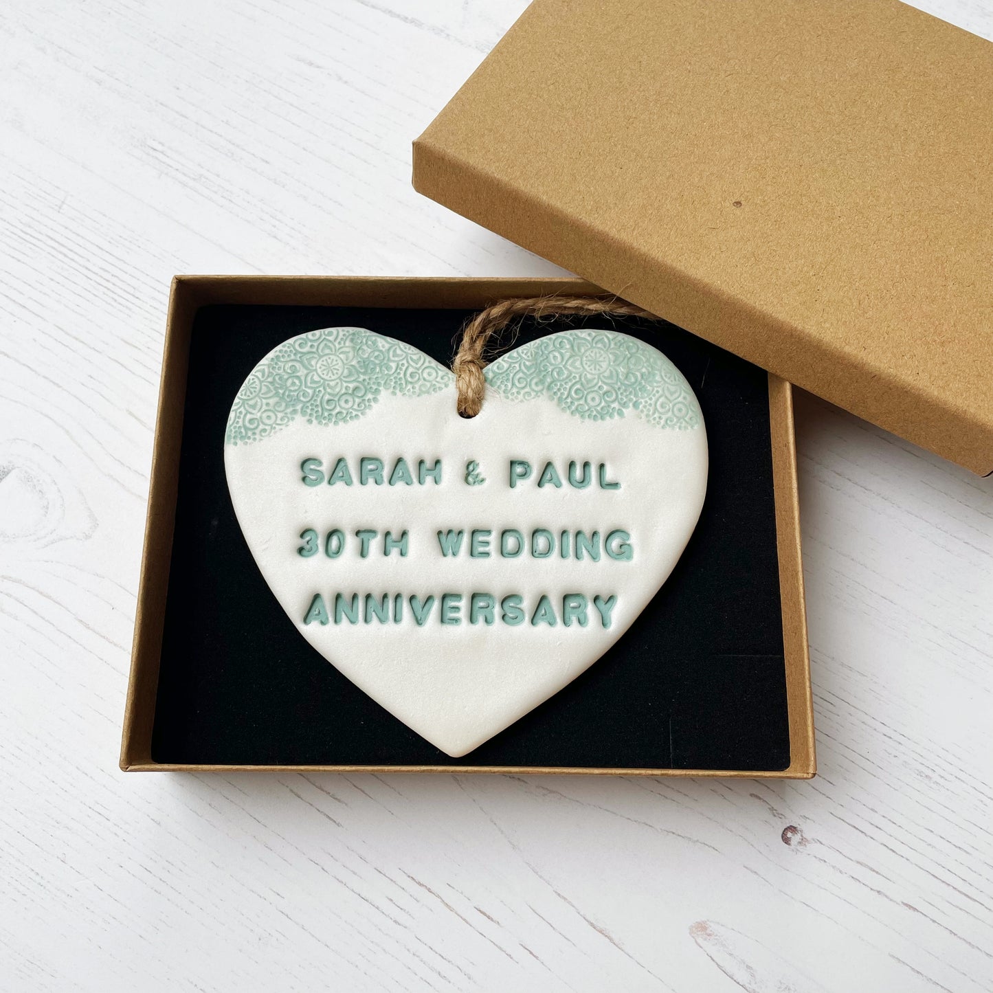 Personalised 30th anniversary gift, pearlised white clay hanging heart with a sage green lace edge at the top of the heart, the heart is personalised with SARAH & PAUL 30TH WEDDING ANNIVERSARY