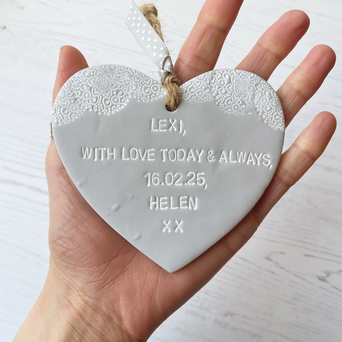 Personalised Christening gift, grey clay hanging heart with baby feet cut out of the bottom and white lace edge at the top of the heart, the heart is personalised with LEXI, WITH LOVE TODAY & ALWAYS, 16.02.25, HELEN XX