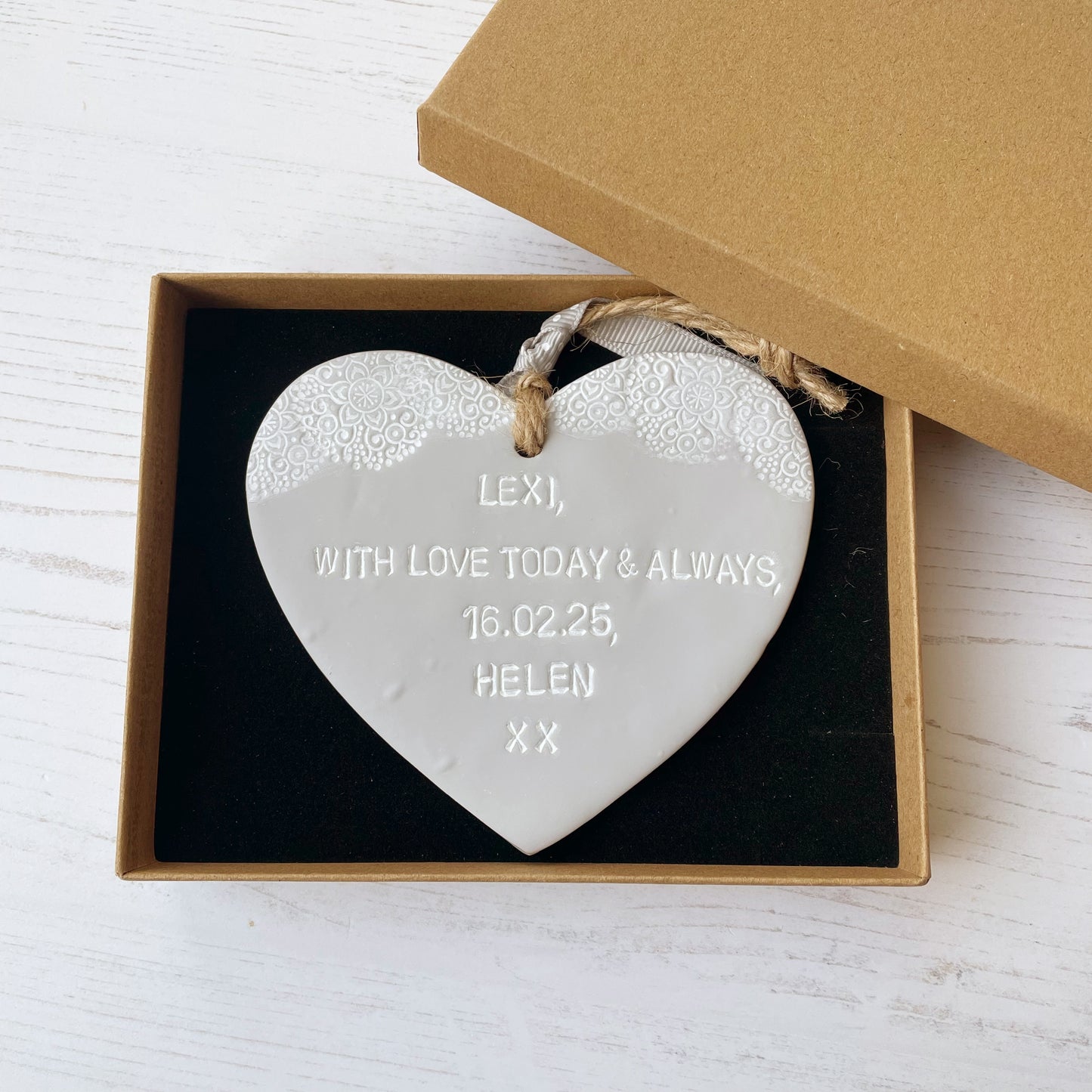 Personalised Christening gift, grey clay hanging heart with baby feet cut out of the bottom and white lace edge at the top of the heart, the heart is personalised with LEXI, WITH LOVE TODAY & ALWAYS, 16.02.25, HELEN XX