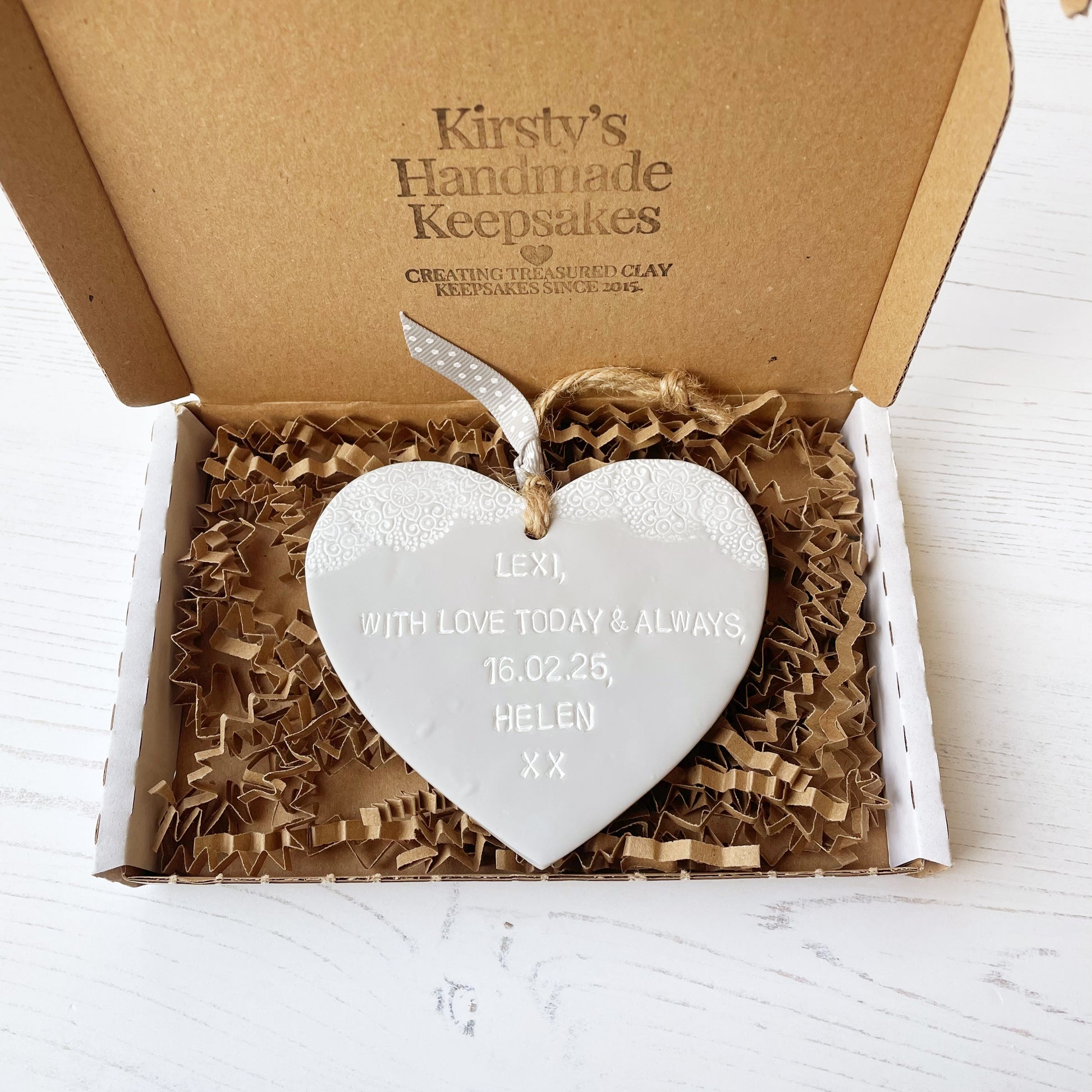 Personalised Christening gift, grey clay hanging heart with baby feet cut out of the bottom and white lace edge at the top of the heart, the heart is personalised with LEXI, WITH LOVE TODAY & ALWAYS, 16.02.25, HELEN XX