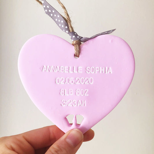 Personalised baby keepsake gift, pastel pink hanging clay heart with baby feet cut out at the bottom of the heart, the heart is personalised with the baby’s name, date of birth, weight and time