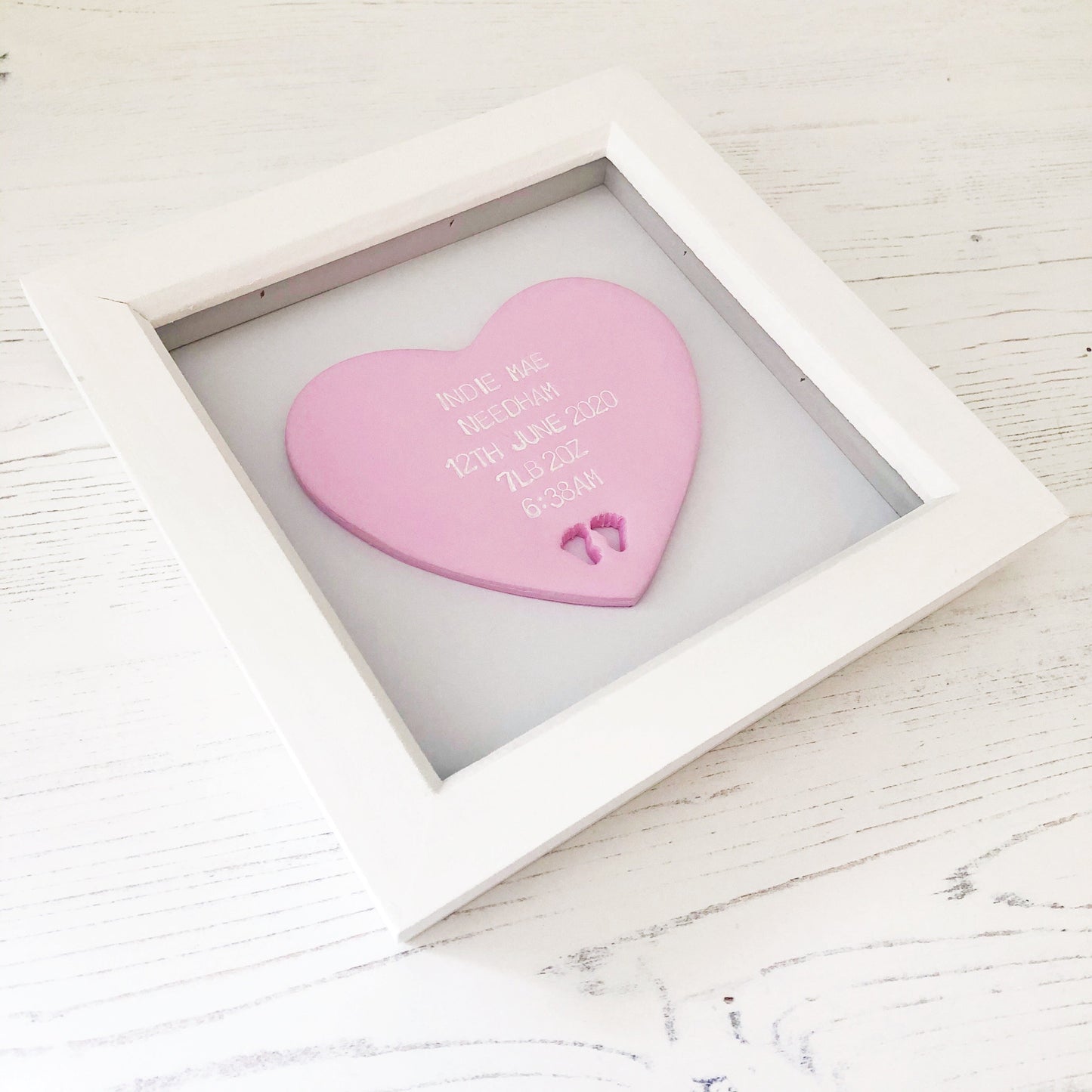 Personalised baby keepsake gift, pastel pink clay heart with baby feet cut out at the bottom of the heart in a white box frame, the heart is personalised with the baby’s name, date of birth, weight and time