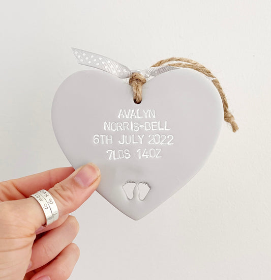 Personalised baby keepsake gift, grey clay hanging heart with baby feet cut out at the bottom of the heart, the heart is personalised with the baby’s name, date of birth, weight and time