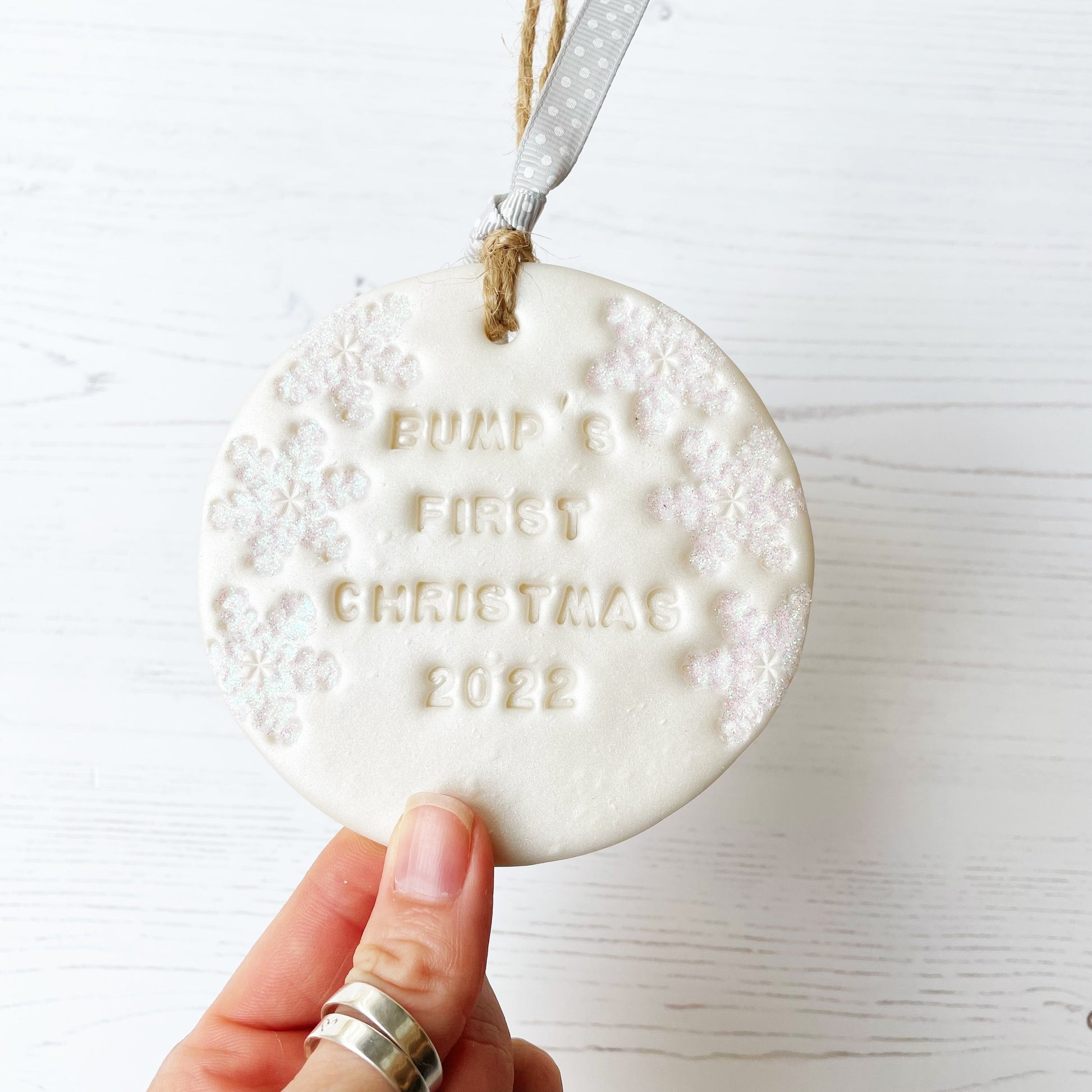 Personalised bump's first Christmas bauble ornament, pearlised white round clay with BUMP’S FIRST CHRISTMAS 2022 (text not painted), decorated with 3 iridescent glitter snowflakes on either side of the bauble