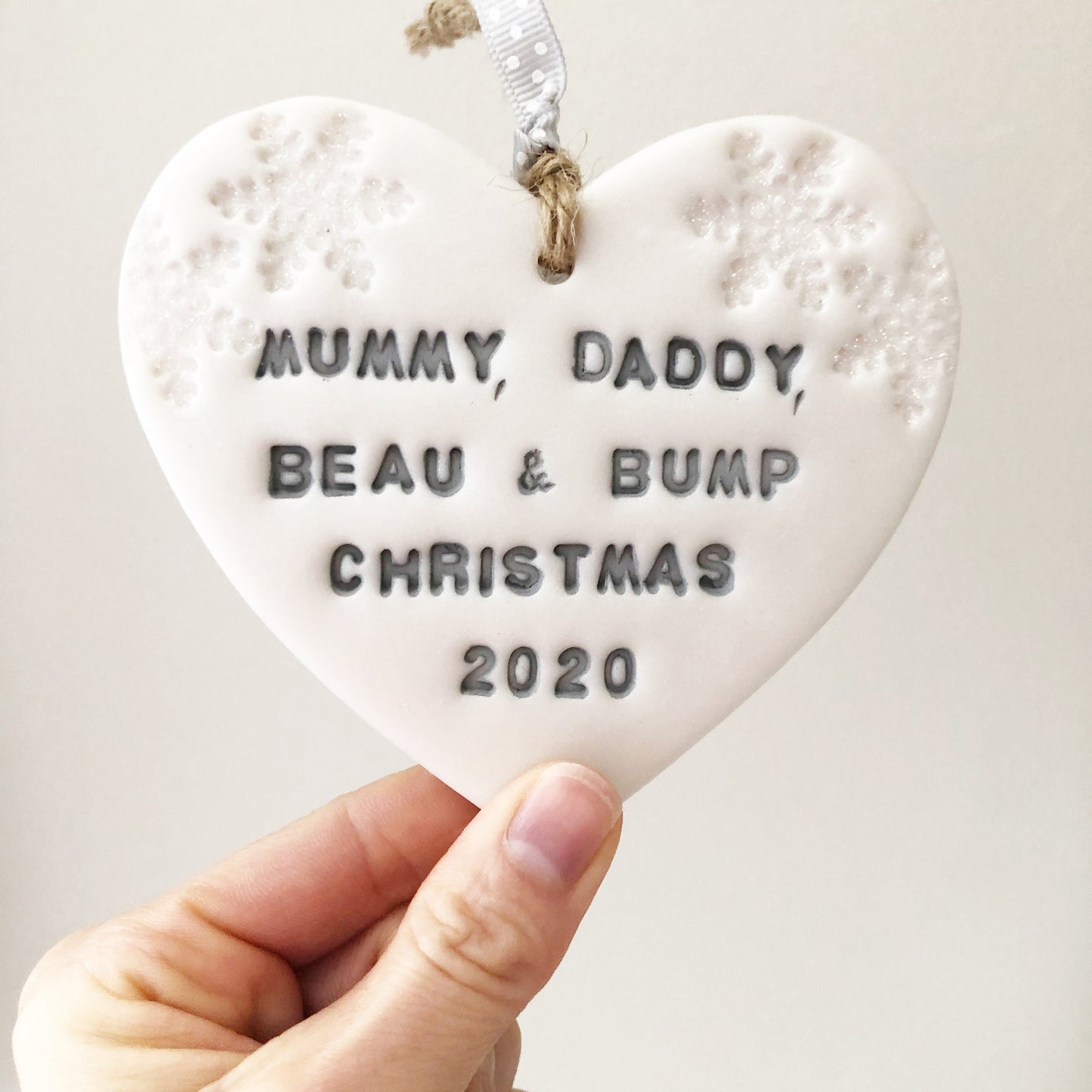 Personalised bump's first Christmas heart ornament, pearlised white clay with MUMMY, DADDY, BEAU & BUMP CHRISTMAS 2020 painted grey, decorated with 2 iridescent glitter snowflakes on either side of the top of the heart