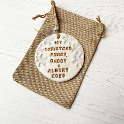 Personalised baby’s first Christmas bauble ornament, pearlised white clay round personalised with 1ST CHRISTMAS MUMMY, DADDY & ALBERT 2025 in gold paint, decorated with 3 iridescent glitter snowflakes on either side of the bauble