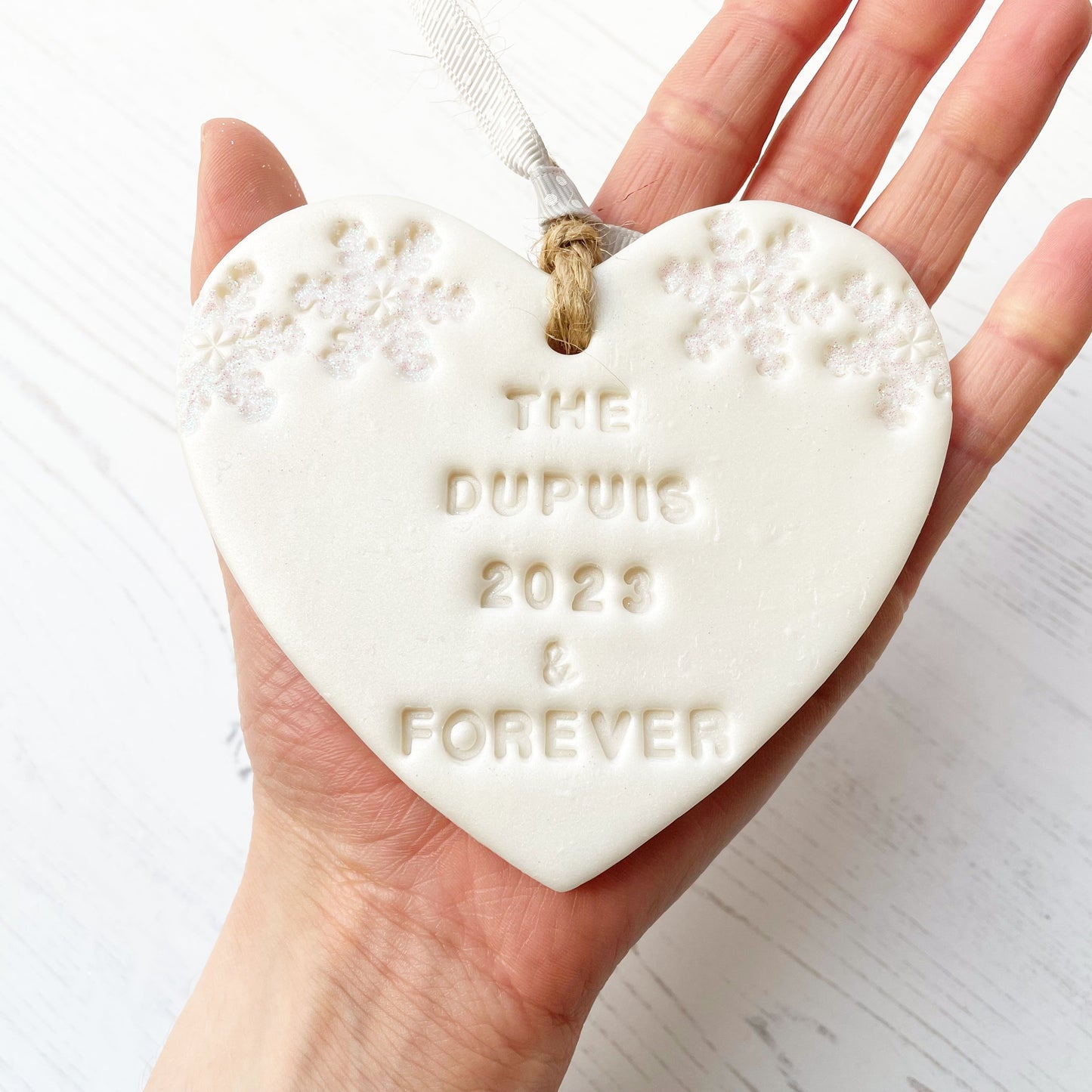 Personalised first Christmas married heart ornament, pearlised white clay with THE DUPUIS 2023 & FOREVER (text not painted), decorated with 2 iridescent glitter snowflakes on either side of the top of the heart