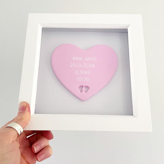 Personalised baby keepsake gift, pastel pink clay heart with baby feet cut out at the bottom of the heart in a white box frame, the heart is personalised with the baby’s name, date of birth, weight and time