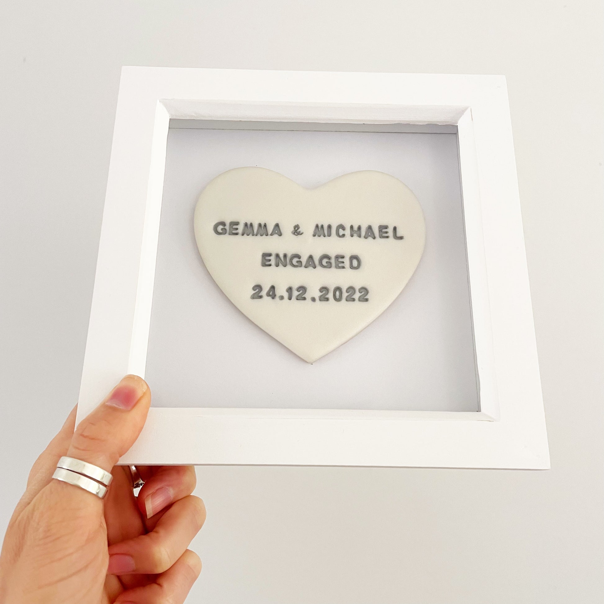 Personalised framed engagement gift, pearlised white clay heart in a white box frame, the heart is personalised with GEMMA & MICHAEL ENGAGED 24.12.2022