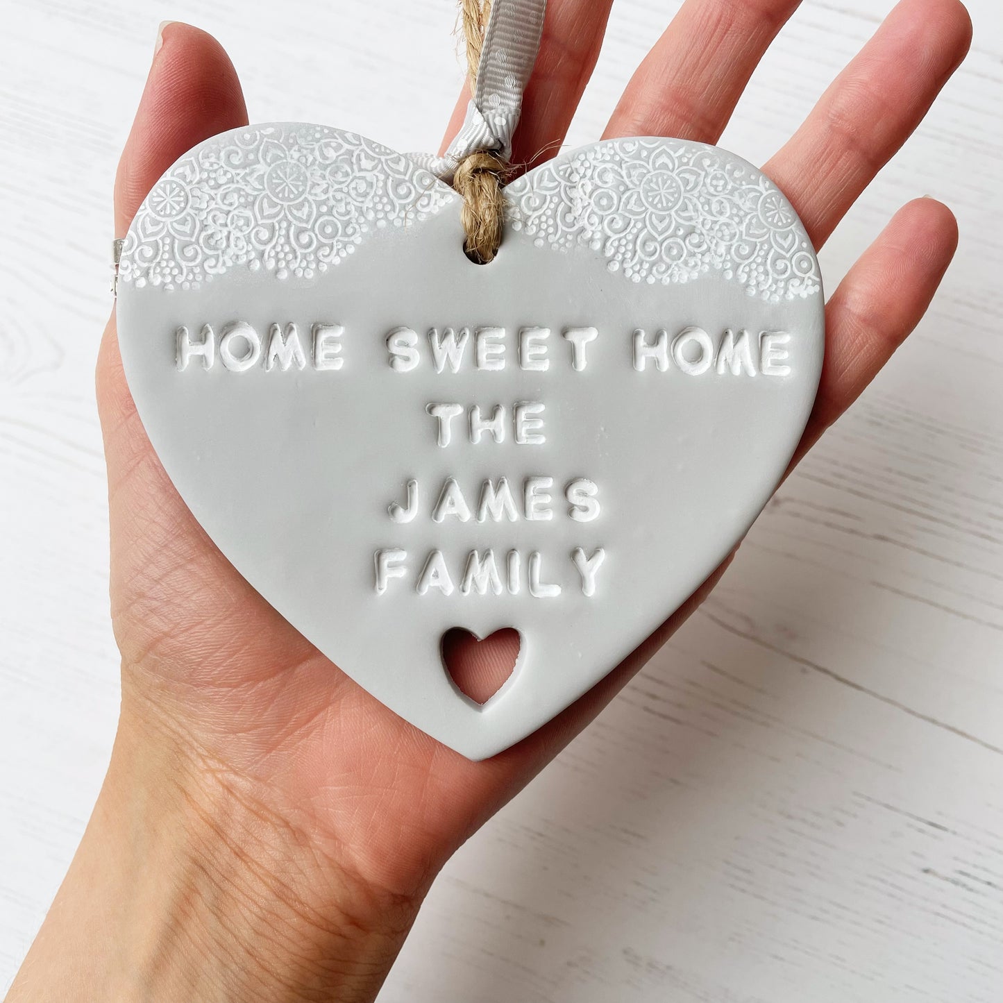 Personalised new home gift grey clay heart with a white lace edge at the top & a heart cut out at the bottom with twine for hanging personalised with HOME SWEET HOME THE JAMES FAMILY