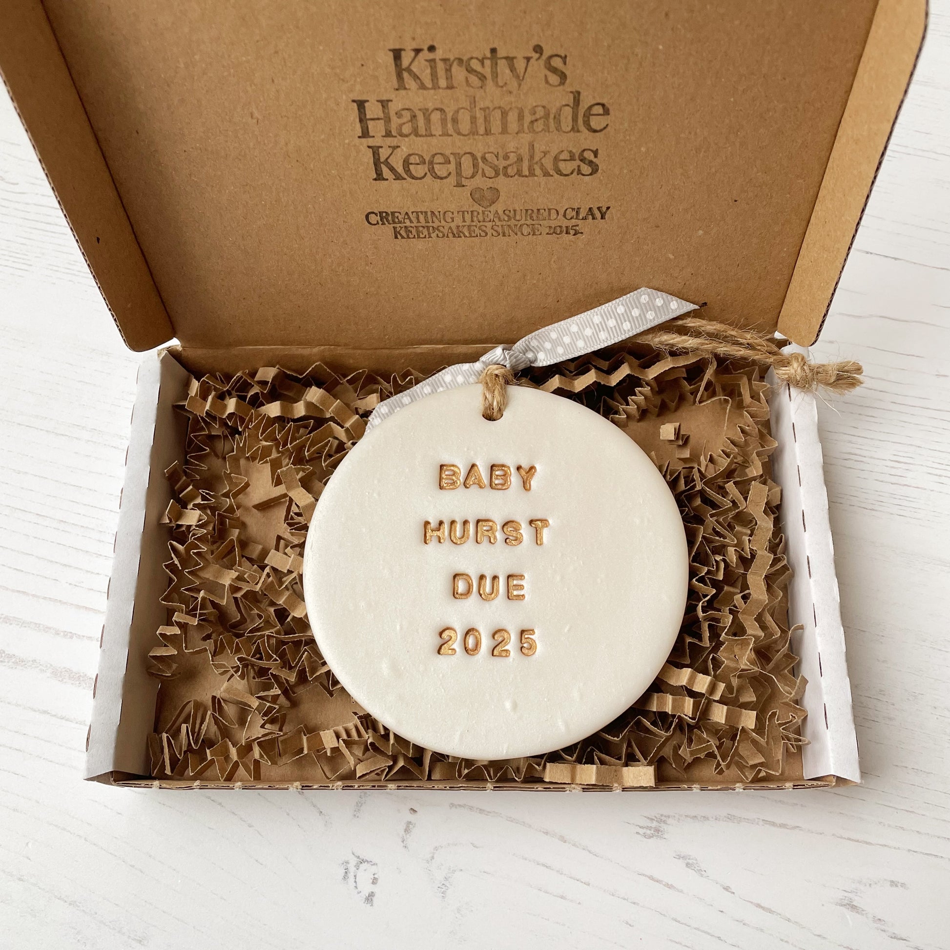 Personalised pregnancy reveal Christmas bauble ornament, pearlised white round clay with BABY HURST DUE 2025 in gold paint