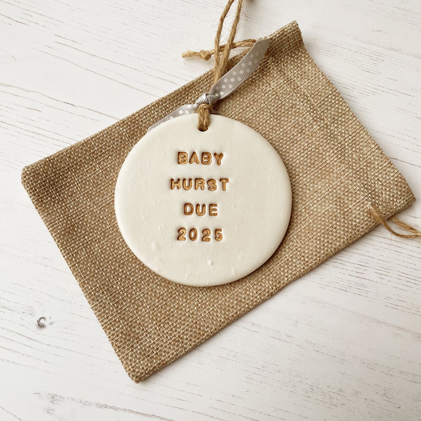 Personalised pregnancy reveal Christmas bauble ornament, pearlised white round clay with BABY HURST DUE 2025 in gold paint